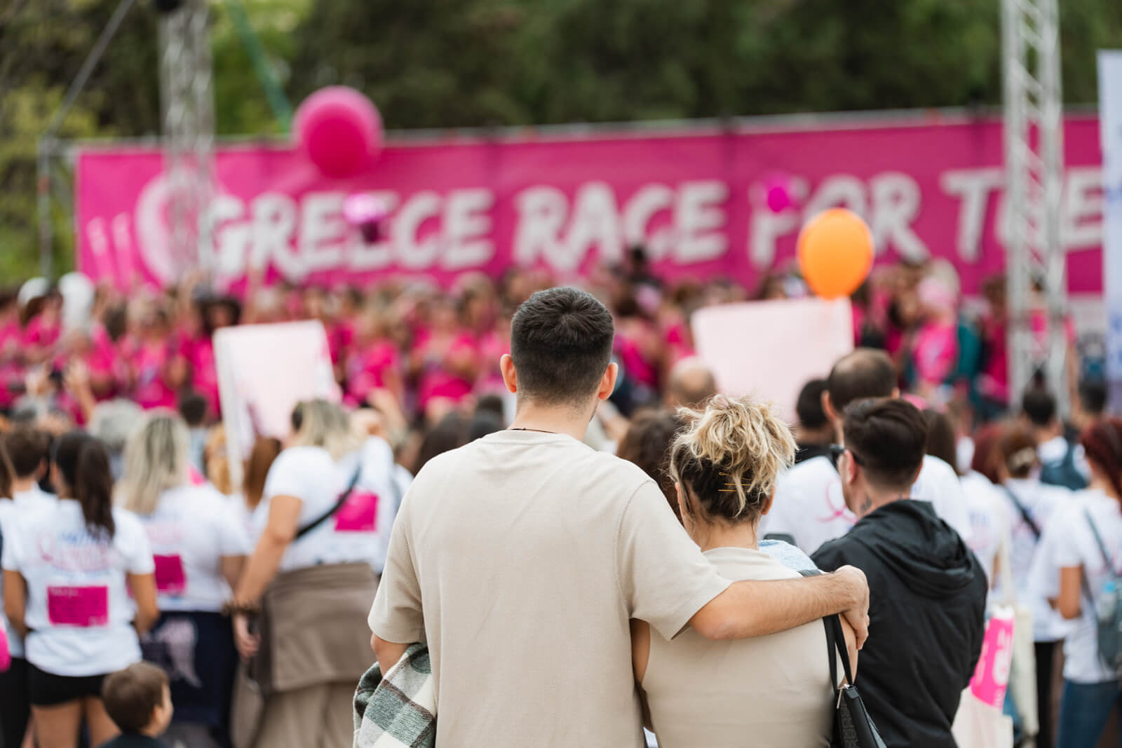 Ζευγάρι ανθρώπων παρακολουθεί τη σκηνή του Greece Race for the Cure® αγκαλιά