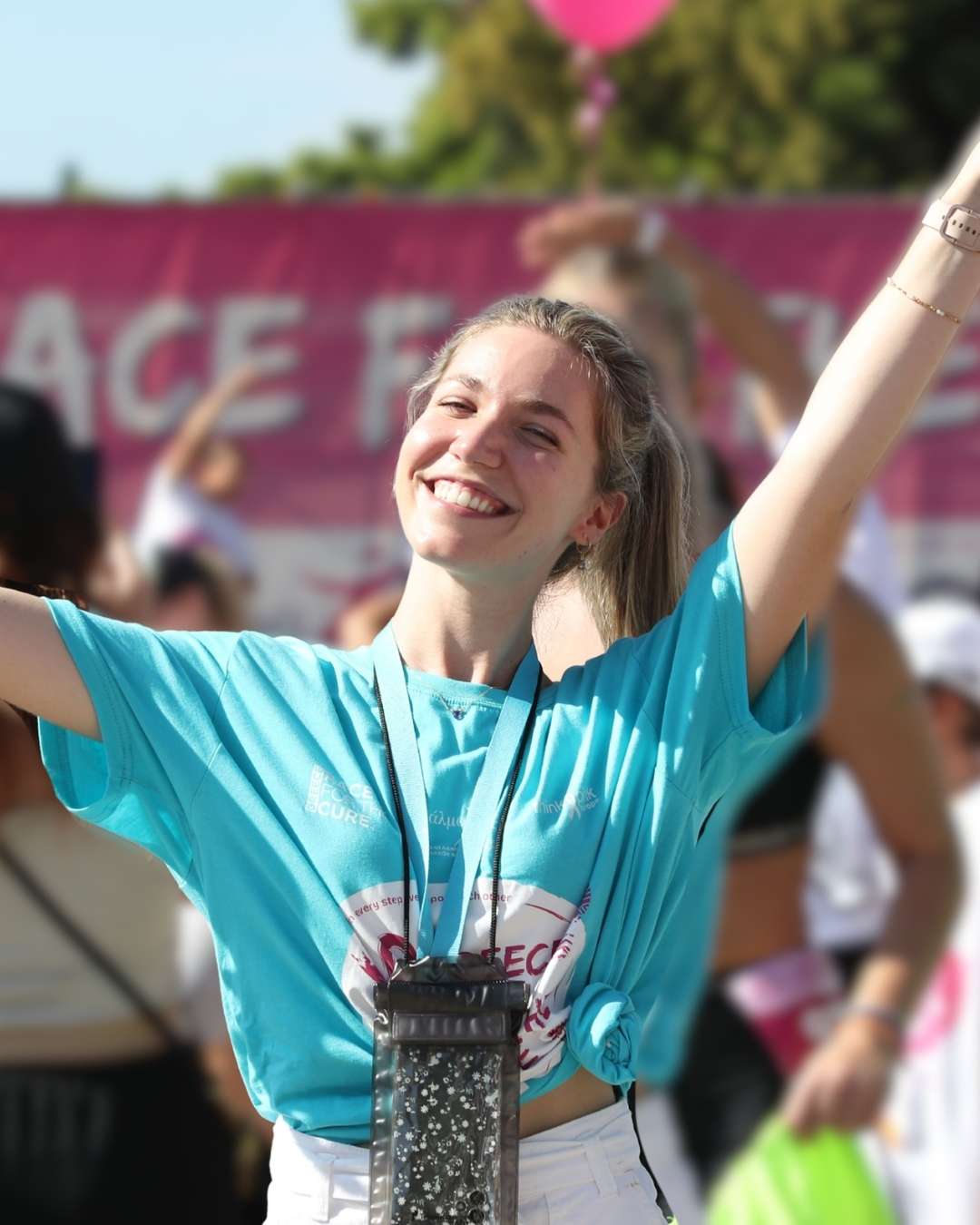 Εθελόντρια του Greece Race for the Cure® χαμογελάει με τα χέρια στον αέρα
